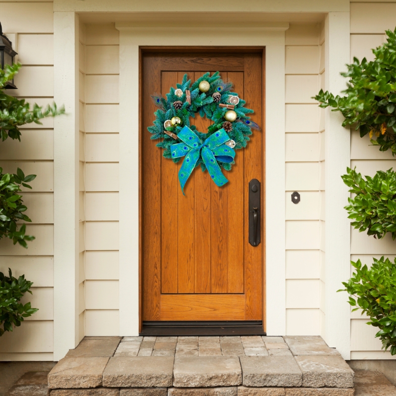 This striking fresh spruce wreath is adorned with scented cinnamon, dried lime slices, pine cones, gold baubles and those bold peacock feathers and matching bow. 