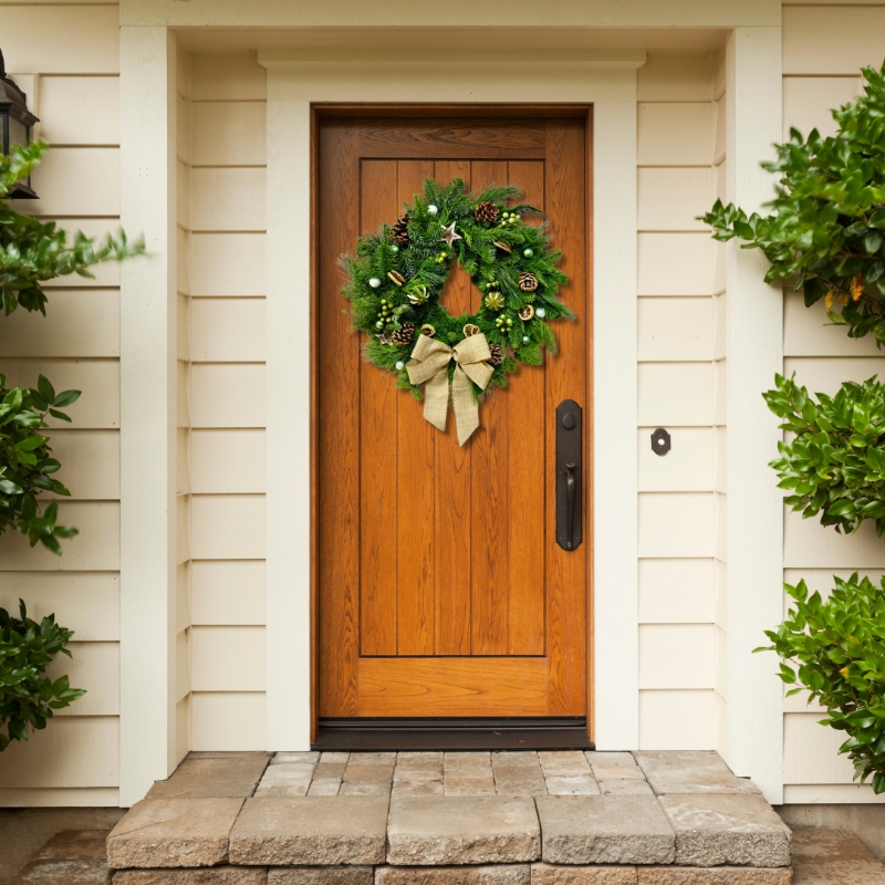 Fresh foliage door wreath filled with lime slices, pine cones and green berries finished with a hessian bow.