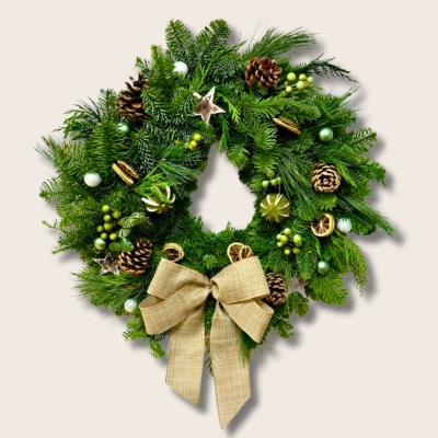 Fresh foliage door wreath filled with lime slices, pine cones and green berries finished with a hessian bow.