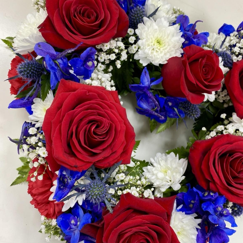 A mixed floral open heart funeral tribute in the British colours of red, white and blue. 