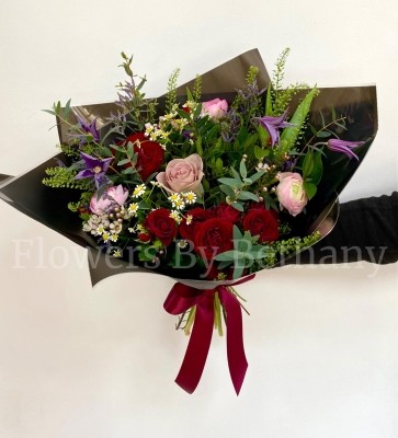 Natural hand tied bouquet filled with rich red and pink tones. Design including roses, clematis and a mix of other seasonal favourites. 