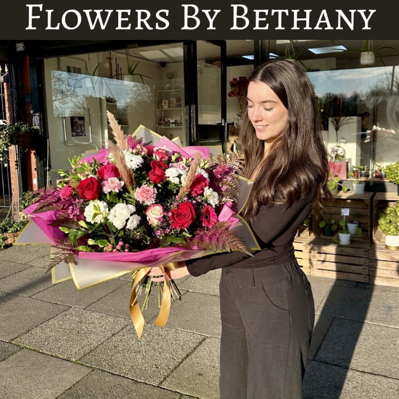 Romantic AF bouquet featuring red roses, pink germini, white chrysanthemums, and carnations with gold-leaf accents, wrapped in pink and gold cellophane hand tied in water. 