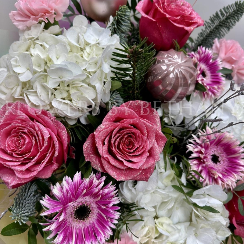 Snow Fairy Christmas bouquet featuring white hydrangea, pink snowy glitter roses, silver birch branches, mixed seasonal pink florals, pink baubles, and iridescent wrap, presented in a matching gift bag.