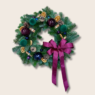 Fresh foliage door wreath with jewel toned accent baubles, dried orange slices, pine cones and cinnamon all brought together with a plush burgundy bow. 