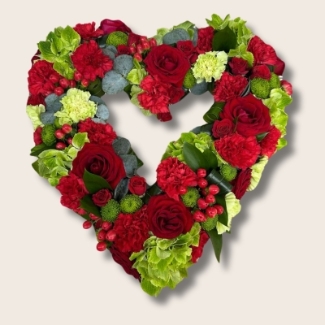 A beautiful red and green mixed open heart funeral tribute filled with seasonal florals. 