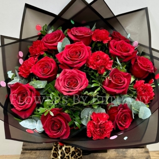 A new Valentine’s Day bouquet featuring red roses and carnations, wrapped in black cherry-print cellophane and topped with a detachable leopard print bow that doubles as a hair clip.