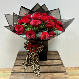 A new Valentine’s Day bouquet featuring red roses and carnations, wrapped in black cherry-print cellophane and topped with a detachable leopard print bow that doubles as a hair clip.