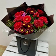 Sparkling bouquet featuring luxury red Freedom roses, red carnations, and red hypericum berries, accented with diamante centers, red glitter, and a pink butterfly, wrapped in luxury cellophane and matching gift bag, hand-tied in water.