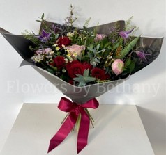 Natural hand tied bouquet filled with rich red and pink tones. Design including roses, clematis and a mix of other seasonal favourites. 