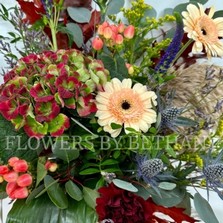 Medium orange pumpkin with floral arrangement including oak leaf, eucalyptus, germini, berries & other seasonal verities. 