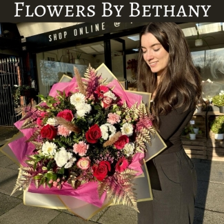 Romantic AF bouquet featuring red roses, pink germini, white chrysanthemums, and carnations with gold-leaf accents, wrapped in pink and gold cellophane hand tied in water. 