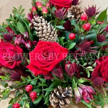 Mixed red bouquet including roses, alstroemeria, hypericum and thistle. Wrapped in kraft paper and displayed in a kraft bag. 