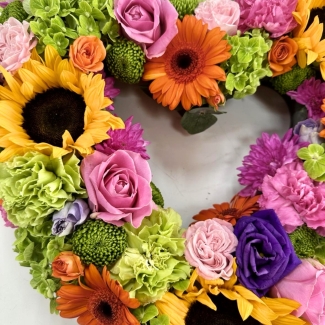 Open heart funeral tribute filled with summer tones including green hydrangea, pink roses, orange germini and purple lisianthus to name a few. 