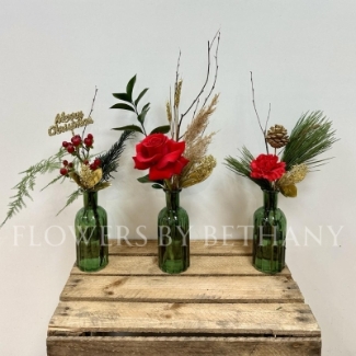 A trio of green glass vases, each filled with red florals, festive foliage and a sprinkle of gold décor. The perfect set for your table centrepiece this Christmas. 