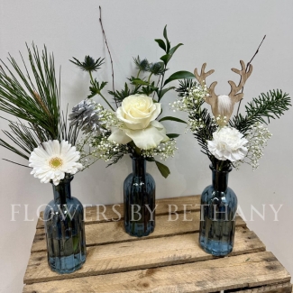 A gorgeous trio of deep blue bottles, each filled with festive foliage, crisp white florals and silver accent décor. The perfect item to dress your home or gift this Christmas. 