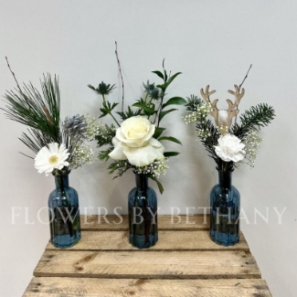 A gorgeous trio of deep blue bottles, each filled with festive foliage, crisp white florals and silver accent décor. The perfect item to dress your home or gift this Christmas. 